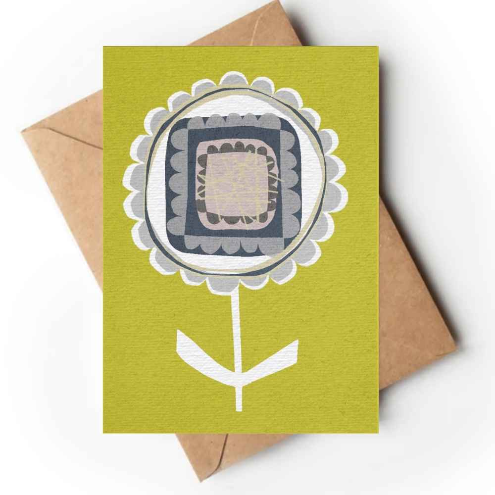 A rectangular greeting card with a stylized flower illustration in olive green, white, gray, and black, shown with a brown kraft envelope behind it on a white background.
