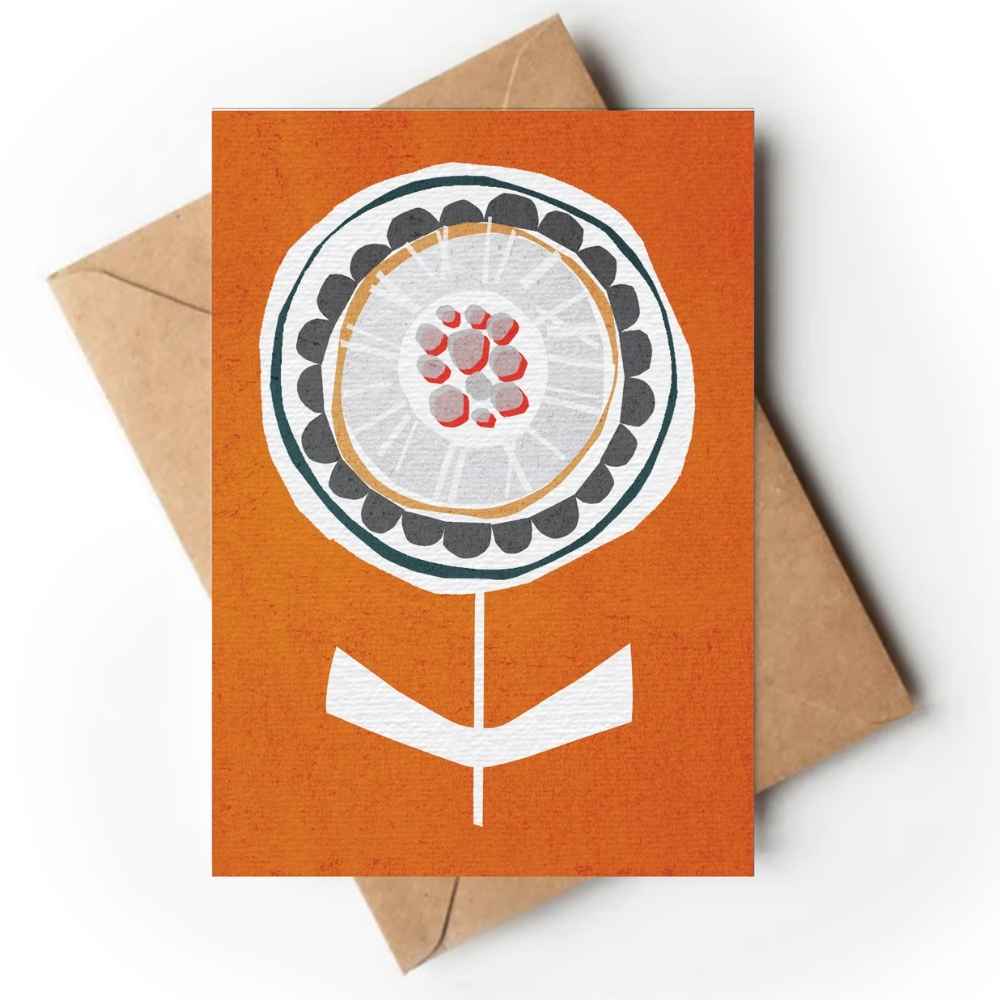 An orange greeting card with a stylized flower illustration, shown with a brown kraft envelope behind it on a white background.