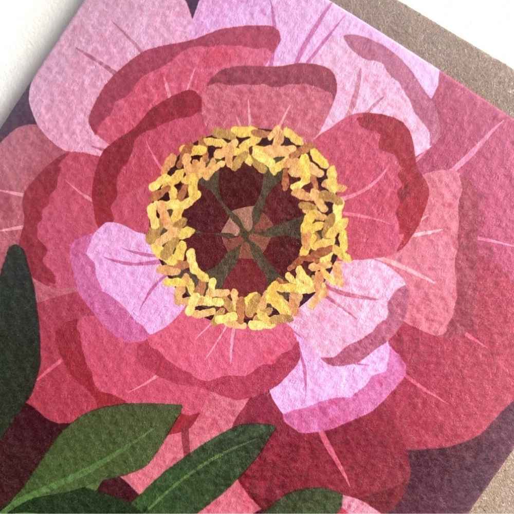 A close-up of a pink Theia peony greetings card, a yellow ring around the center, and green leaves on a dark background.